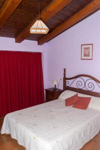 1 dormitorio con 1 cama grande y cortina roja en Casa Rural Benito, en Las Cuevas de Cañart