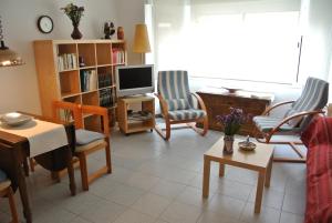 sala de estar con TV, sillas y mesa en Aiguaneu Apartaments Center, en Blanes