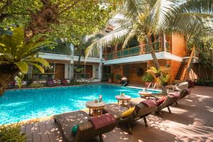a pool with chairs and tables next to a building at Pingviman Hotel in Chiang Mai