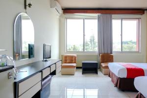 Cette chambre comprend un lit et un bureau avec une télévision. dans l'établissement Hotel Bandung Permai Jember, à Jember