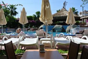 un grupo de mesas y sillas con sombrillas junto a una piscina en Begonville Hotel, en Marmaris