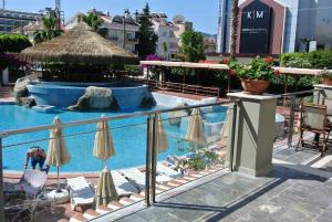 a swimming pool with chairs and umbrellas and a person in avisor at Begonville Hotel in Marmaris