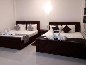 two swans are sitting on two beds in a room at Airport Grand Holiday Home in Katunayaka