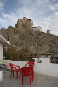 two red chairs and a castle on a hill at Hotel Khan Manzil in Leh