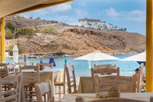 Parathinalos Beach House في ليفاذيا أستيبالياس: مجموعة من الطاولات والكراسي على شاطئ مع المحيط
