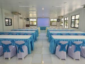 LayTrang Pakmeng Marina Spa and Resort في ترانغ: غرفة بها طاولات وكراسي زرقاء وشاشة