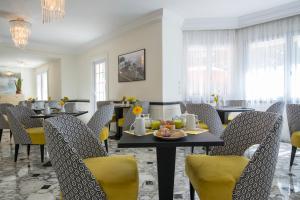 a dining room with tables and yellow chairs at Hotel Carlton in Beaulieu-sur-Mer