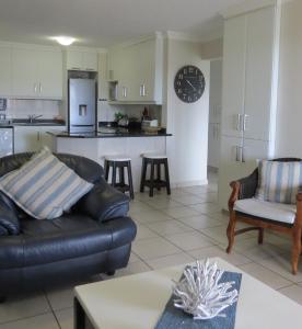 a living room with a couch and a kitchen at Laguna 75 in Uvongo Beach