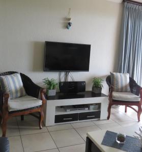 a living room with two chairs and a flat screen tv at Laguna 75 in Uvongo Beach