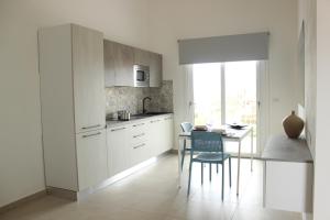una cocina con armarios blancos y una mesa con una silla en 197 Pozzo San Nicola, en Stintino