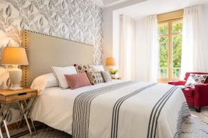 a bedroom with a bed and a red chair at Genteel Home Zegrí in Málaga
