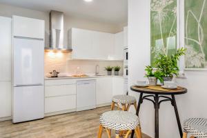 a kitchen with white cabinets and a table and chairs at Genteel Home Zegrí in Málaga
