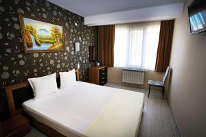 Un dormitorio con una gran cama blanca y una ventana en Apart Hotel Central, en Momchilgrad