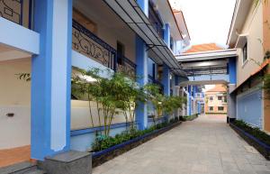 a corridor of a building with blue columns and plants at Nhà Khách Làng May Mắn - Village Chance in Ho Chi Minh City