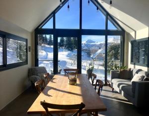 a living room with a wooden table and a large window at Chez Mary Elise in Le Claux