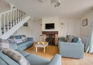 a living room with two blue couches and a fireplace at Hafan y Traeth (Sandy Haven) in Herbrandston