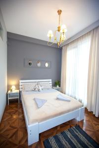 um quarto com uma cama branca e um lustre em Tbilisi LOA Apartment em Tbilisi