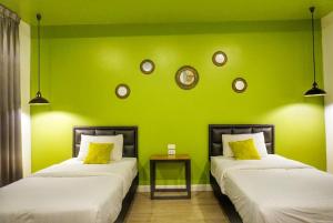 two beds in a room with a green wall at Manonnee in Chiang Rai
