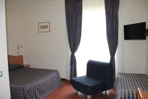 um quarto com uma cama, uma cadeira e uma janela em B&B Luna Blu em Modica