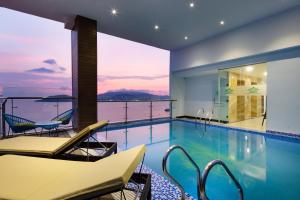 a swimming pool with chairs and a view of the ocean at Crown Hotel Nha Trang in Nha Trang