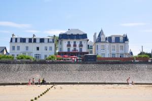 a group of people sitting on the beach near a building at Hôtel Ar Iniz in Saint Malo