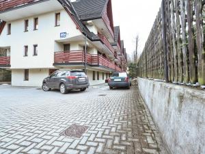 dwa samochody zaparkowane przed budynkiem w obiekcie VisitZakopane - Himalaya Apartment w Zakopanem