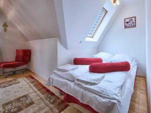 sypialnia z łóżkiem z czerwonymi poduszkami i czerwonym krzesłem w obiekcie VisitZakopane - Himalaya Apartment w Zakopanem