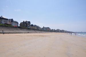 a beach with buildings and people walking on it at Hôtel Ar Iniz in Saint Malo