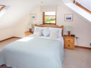 Un dormitorio con una gran cama blanca y una ventana en Cuddy's Croft, en Chatton