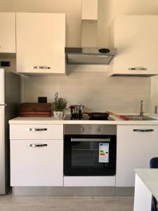 a kitchen with white cabinets and a black oven at Il Miraggio in Fregene