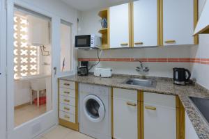 una cucina con lavatrice e lavandino di Residencial Guardamar Zeus a Miami Platja