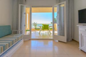 a living room with a sliding glass door with a view of the ocean at Residencial Guardamar Zeus in Miami Platja