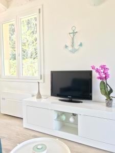 a white living room with a tv on a white cabinet at Il Miraggio in Fregene