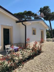 a white house with a table and chairs and flowers at Il Miraggio in Fregene