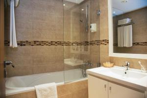a bathroom with a tub and a sink and a shower at AQI Skanes Resort in Monastir