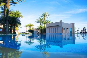 a pool of water with palm trees and a building at AQI Skanes Resort in Monastir