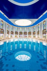 a swimming pool in a building with stained glass windows at AQI Skanes Resort in Monastir
