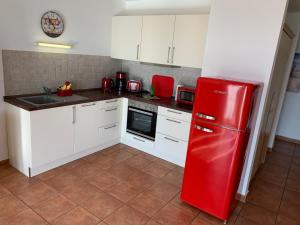 una nevera roja en una cocina con armarios blancos en Apartment "MS Bernstein" (75m²) im Ferienpark en Sagard