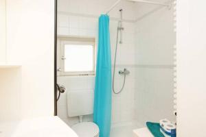 ParkView Apartment 1 في برلين: حمام مع ستارة دش زرقاء ومرحاض