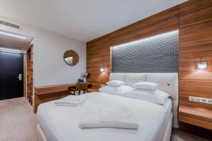 a bedroom with a large white bed with wooden walls at Boutique Hotel Budapest in Budapest