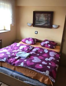 a bedroom with a bed with a purple blanket and pillows at Zajazd Batory in Chorzów