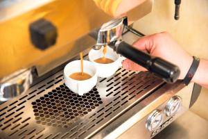 a person is pouring coffee into two cups at AQI Skanes Resort in Monastir