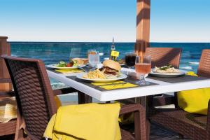 a table with a sandwich and french fries and drinks at AQI Skanes Resort in Monastir