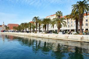 a river in a city with palm trees and buildings at Hotel Adriana in Split