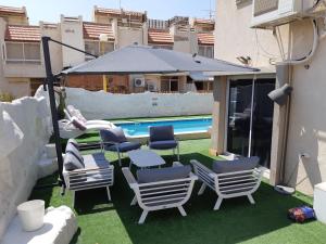 eine Gruppe Stühle und ein Sonnenschirm neben einem Pool in der Unterkunft Villa Sea House in Eilat