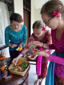 un gruppo di donne che si siedono intorno a un tavolo a preparare il cibo di Krisda Ubud Guest House ad Ubud