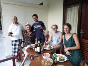 um grupo de pessoas sentadas à volta de uma mesa com garrafas de vinho em Krisda Ubud Guest House em Ubud