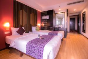 duas camas num quarto de hotel com paredes vermelhas em Mercure Pontianak City Center em Pontianak