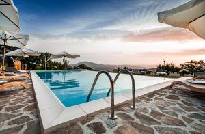 a pool at a resort with chairs and umbrellas at Nikis Resort in Gubbio