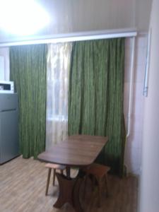 a wooden table in a room with green curtains at Просторная 1комнатня квартира напротив ТРЦ Дафи Ашан рядом ресторан Альтбир in Kharkiv